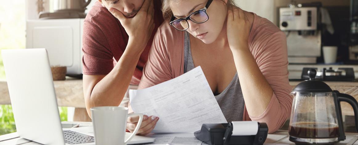 Woman and man looking at a document with calculator on desk